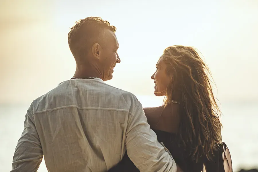 Anti-Aging-Clinic A couple gazes at each other on the beach at sunrise, viewed from behind. Schedule Anti-Aging treatment from Vitality Medical in Seattle.