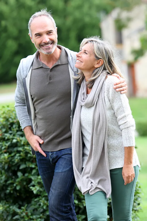 Bioidentical-Hormone-Therapy-Treatment A mature couple in gray toned clothes and jeans walk happily outside, happy with their successful bioidentical hormone treatments from Vitality Medical in Seattle.