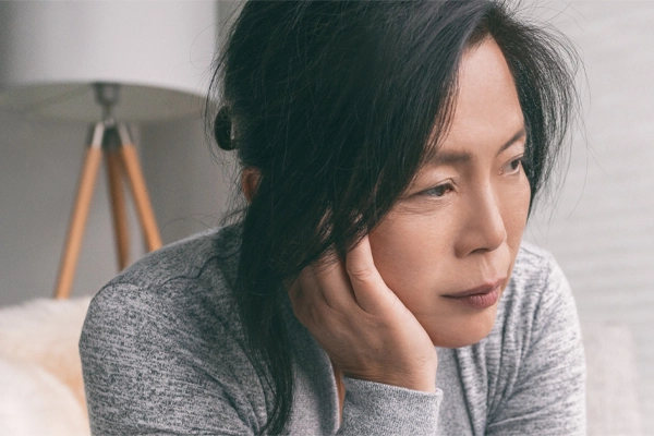 Chronic-Disease-Clinic A middle-aged asian woman rests her head on her hand with exhaustion. Get treatment for chronic disease from Vitality Medical in Seattle.