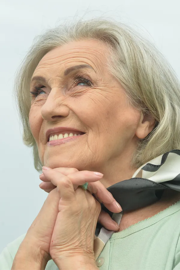 Hot-Flashes-and-Night-Sweats-Treatments An older woman holds her hands together under her chin and looks up at a cool sky smiling. Get treatment for hot flashes and night sweats from Vitality Medical in Seattle.