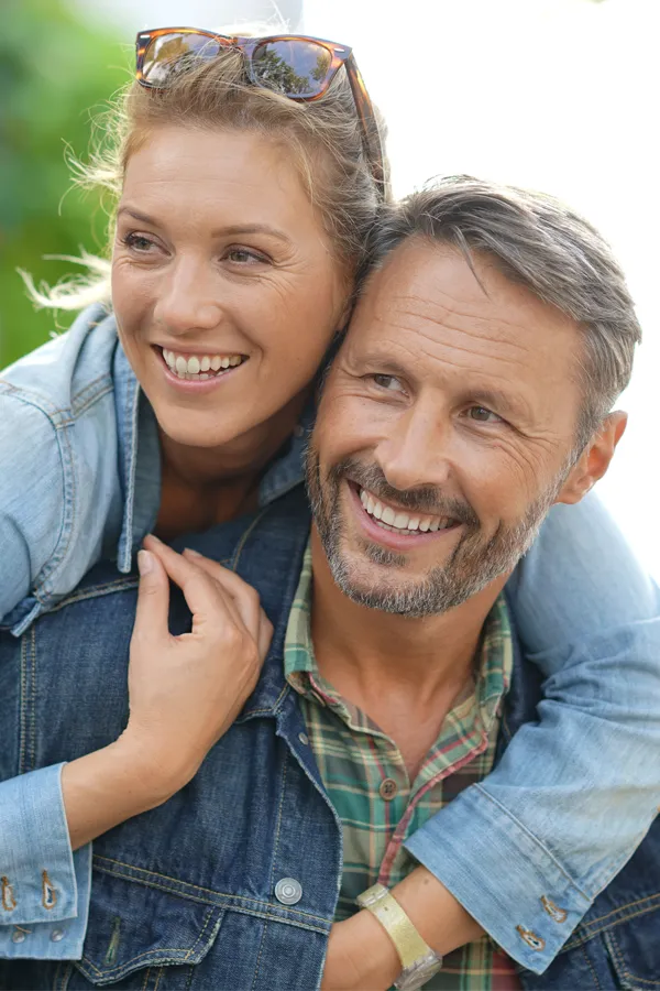 Hypogonadism-Treatment A couple in denim jackets embrace playfully outdoors. Get hypogonadism treatment from Vitality Medical in Seattle.