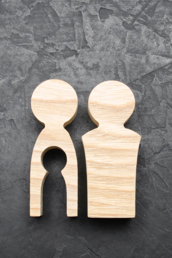 Woodcut figures of a man and woman with a child-shaped area cut out from the woman figure. Get treatment for infertility from Vitality Medical in Seattle.