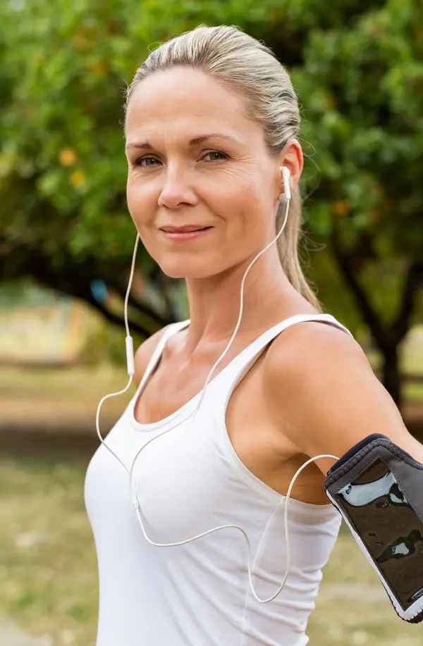 Insulin-Resistance-Treaatment A fit middle aged woman wearing earphones and a tank top smiles after a run. Get insulin resistance treatment from Vitality Medical in Seattle.