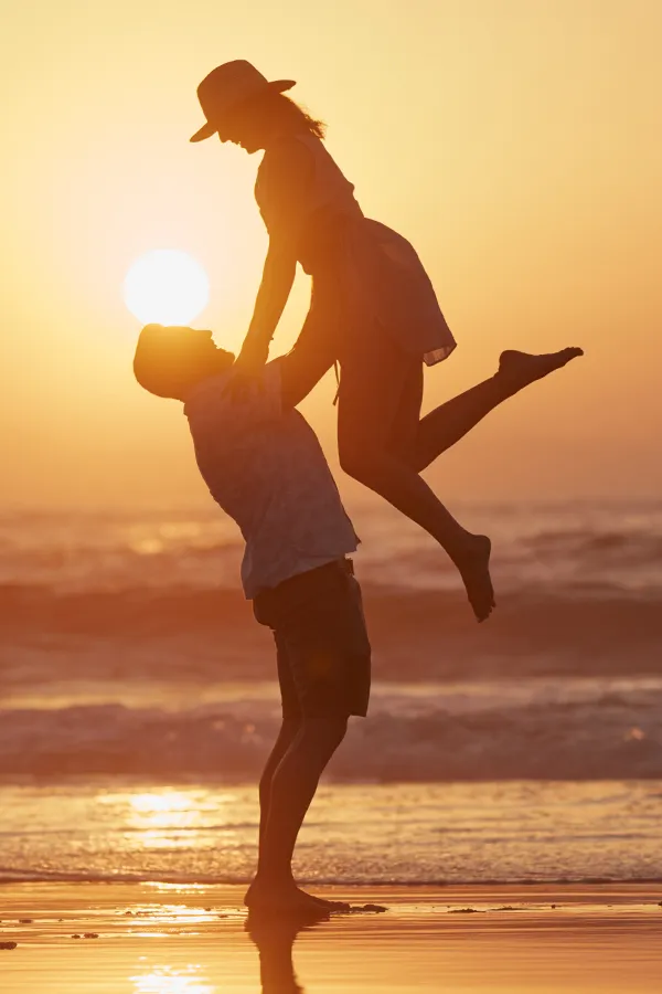 LCL-Tears-Treatment A man lifts a woman into the air on the beach. Get treatment for LCL tears from Vitality Medical in Seattle.