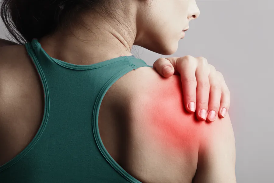 A woman holds her shoulder in pain. Schedule treatment for larum tears from Vitality Medical in Seattle.