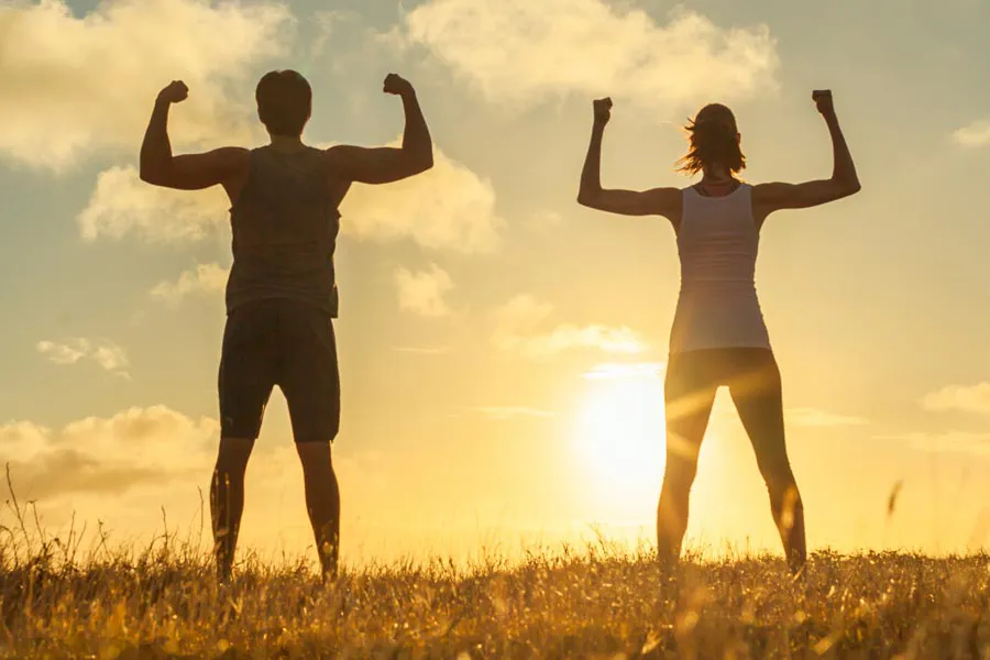 Longevity-Medicine-Clinic Man and woman flexing their arms at sunrise schedule a longevity medicine consultation with Vitality Medical in Seattle.