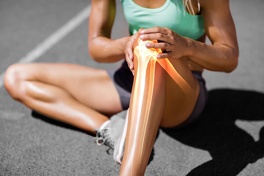 MCL-Tears-Clinic A female runner sits on the track and holds her knee in pain. Schedule treatment for MCL tears from Vitality Medical in Seattle.