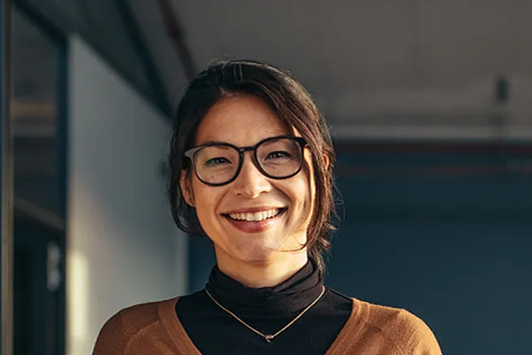 Metabolic-Syndrome-Clinic A brunette woman with glasses smiles in a gray-blue walled office. Get metabolic syndrome from Vitality Medical in Seattle.