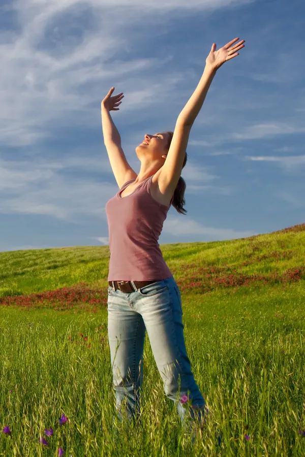 Methylene-Blue-Therapy-Treatment Woman standing in a lush green field with arms raised, representing renewed energy and wellness from methylene blue therapy by Vitality Medical in Seattle.