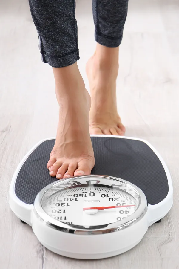 Obesity-Treatment Close up of feet stepping onto a scale. Receive expert functional medicine for obesity treatment by Vitality Medical in Seattle.