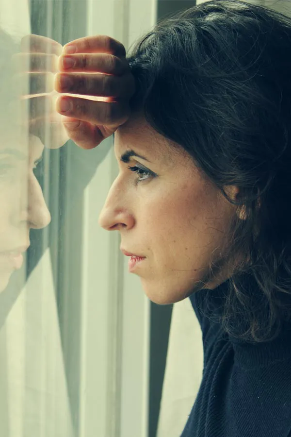 PCOS-Treatment A brunette woman in a thin dark turtleneck looks out the window with a serious expression, suffering from PCOS. Get treatment for Polycistic Ovarian Syndrome/PCOS from Vitality Medical in Seattle.