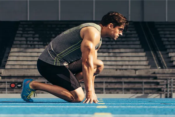 Sermorelin-Clinic With a determined look, Aamuscular man in track clothes kneels at the start of a race. Get Sermorelin peptide therapy from Vitality Medical in Seattle.