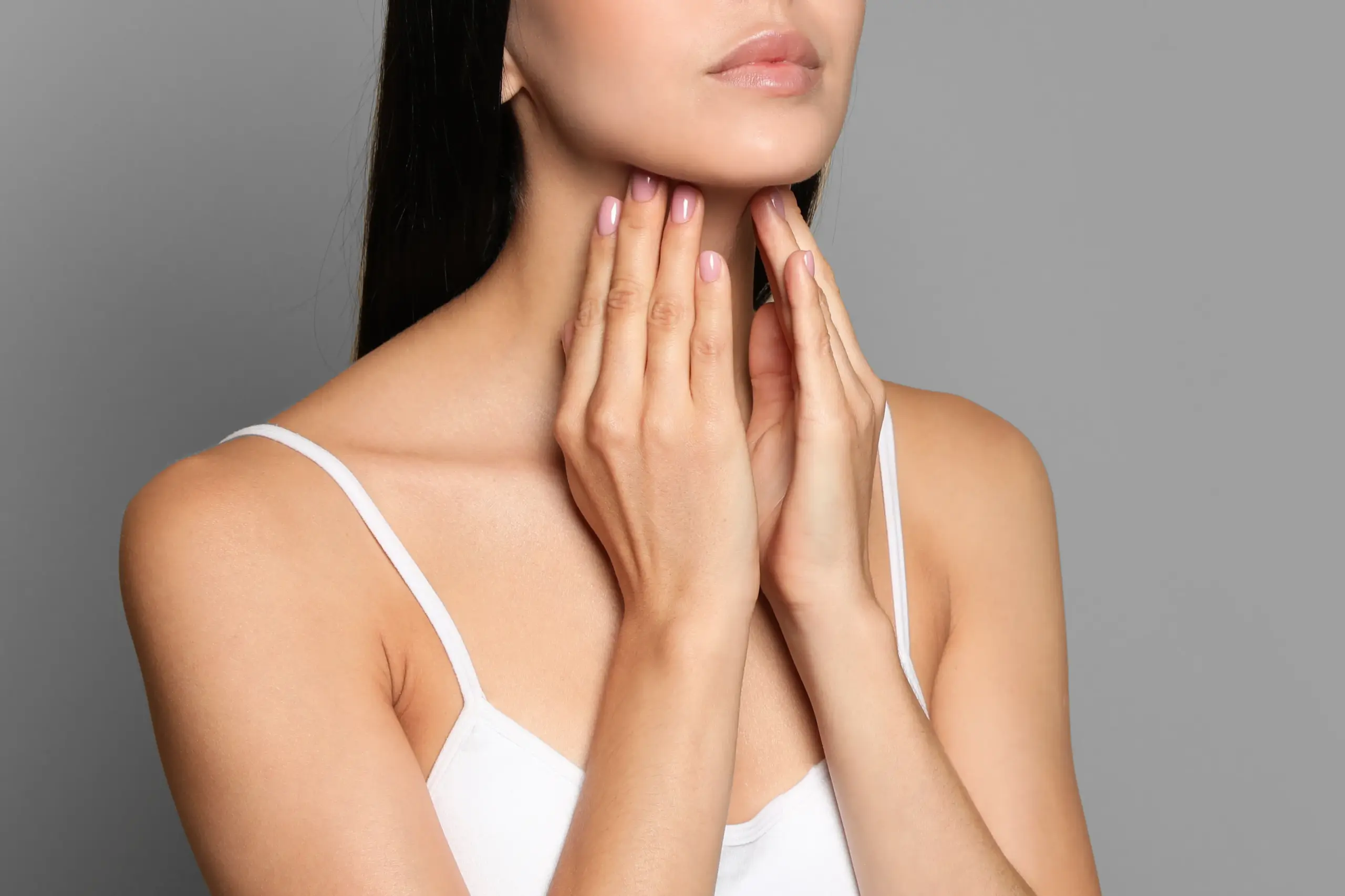 Thyroid-Doctor A woman in a white tank top touches her neck looking for signs of thyroid disorder. Get help for thyroid disorders from Vitality Medical in Seattle.
