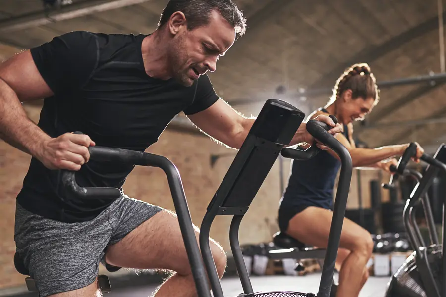 Tirzepatide-Doctor A couple in a brick gym work as hard as they can on exercise bikes, inspired by successful Tirzepatide treatment from Vitality Medical in Seattle.